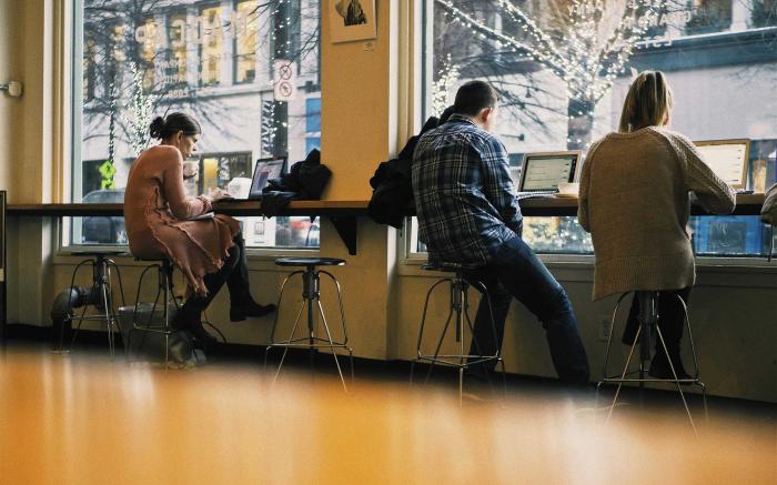 Millennials on laptops in coffee shop.