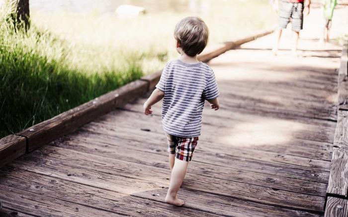 Boy running on wooden bridge.