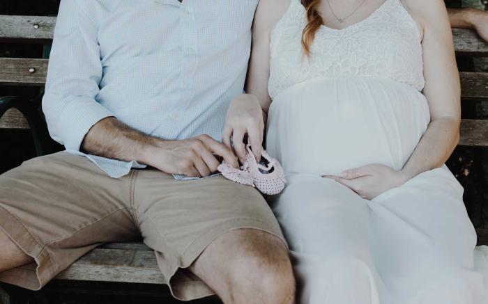 Man and pregnant wife sitting on bench.