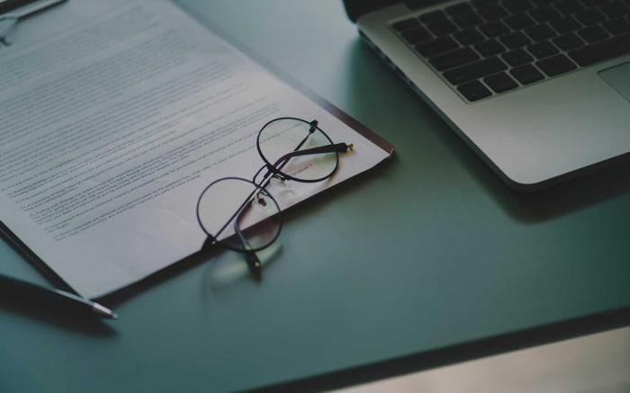 Glasses on a notebook, next to a laptop.